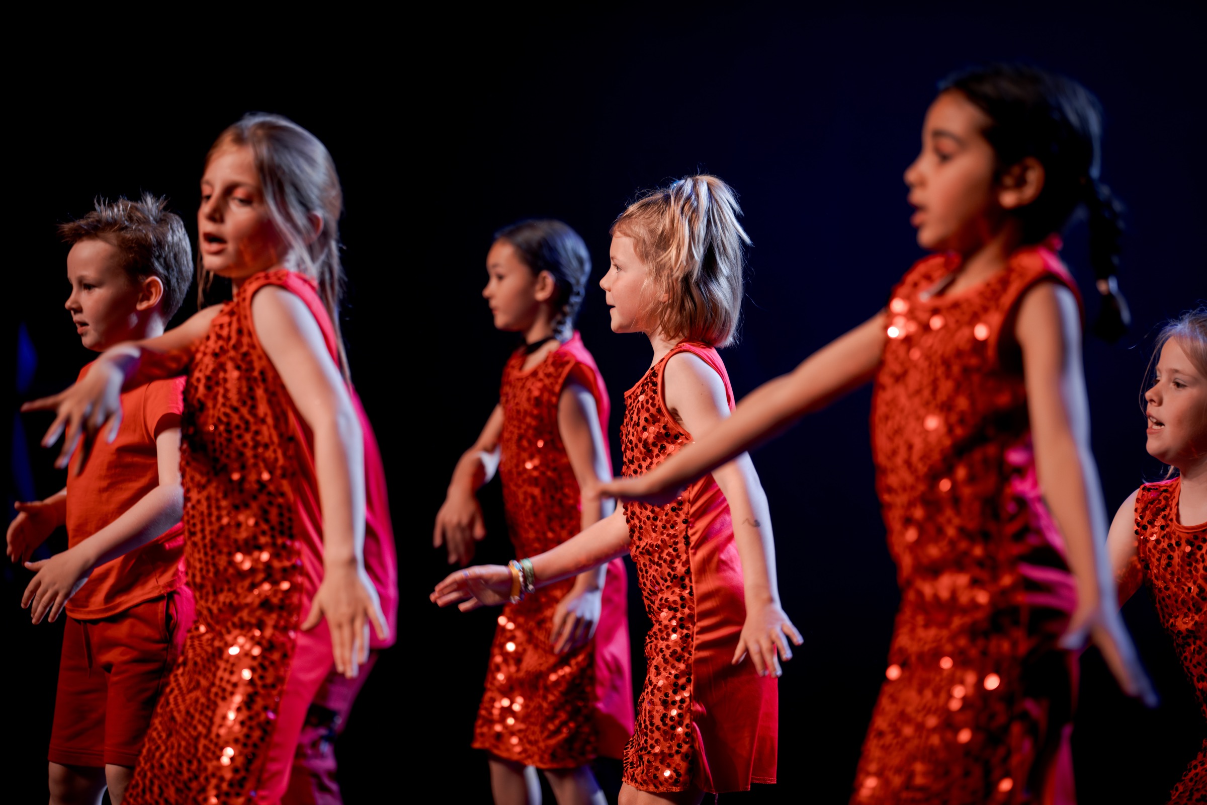 Jonge dansers in rode kostuums tijdens een Invictus-optreden